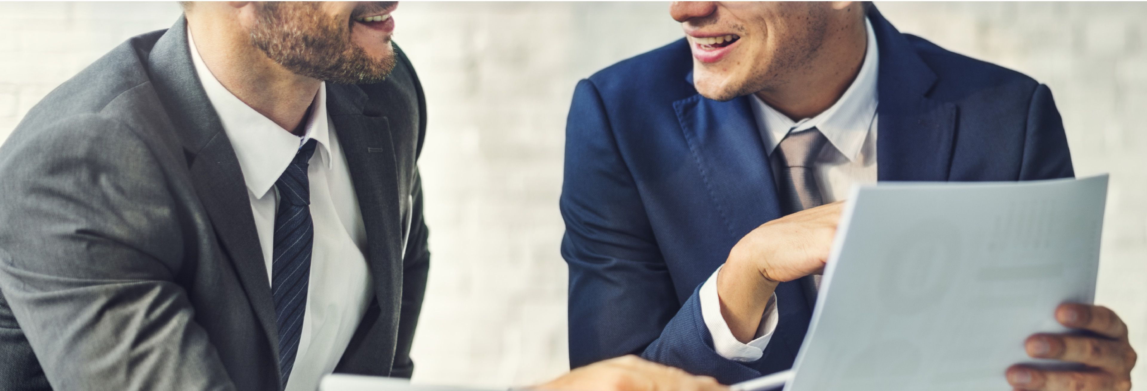 2 Geschäftsmänner, die einen Business Report besprechen und sich gegenseitig zulächeln.