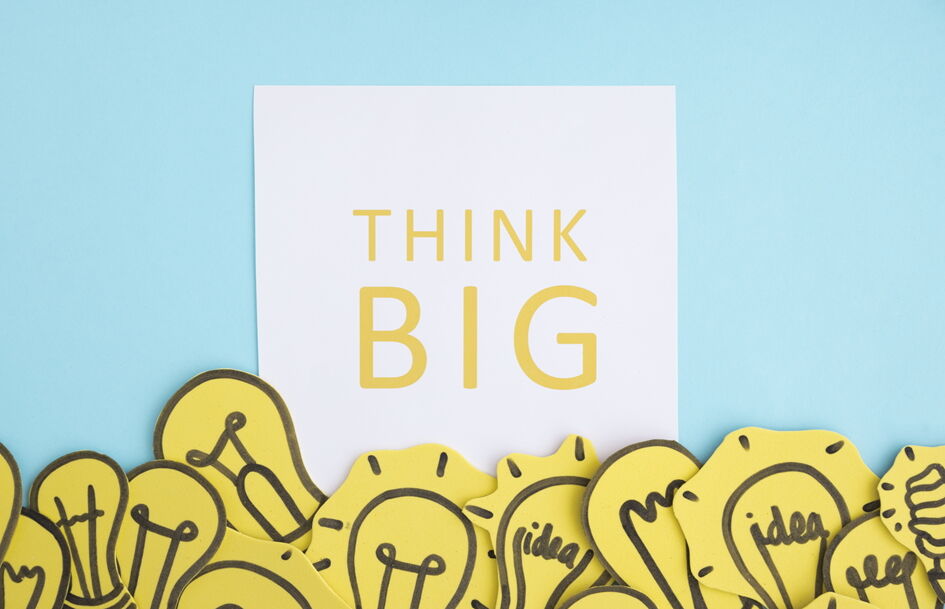 "Think big"-Text unterlegt mit verschiedenen Glühbirnen auf blauem Hintergrund.